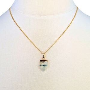 Gold necklace with a blue and white crystal pendant, featuring a unique shield shape.