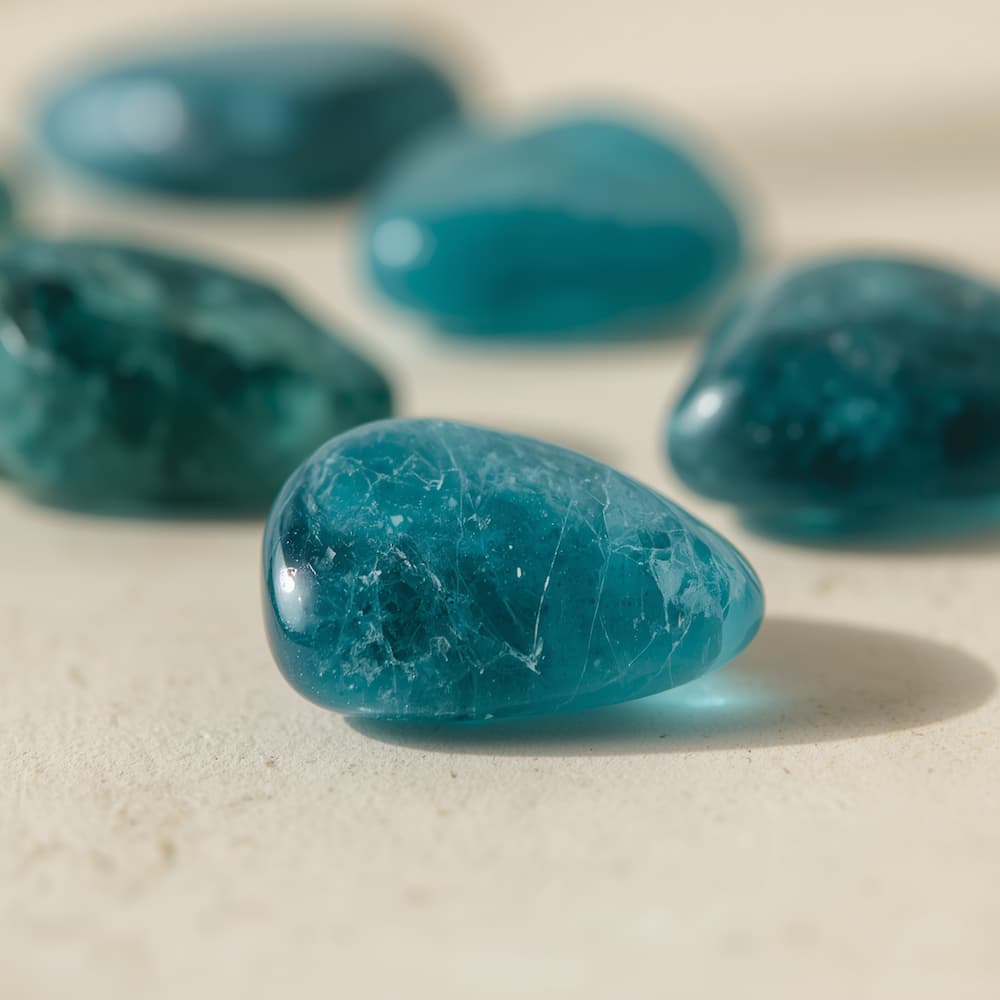 Polished neon blue-green apatite tumbled stones and a faceted blue apatite