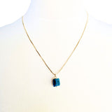 Blue gemstone pendant necklace featuring a gold chain, elegant and stylish.